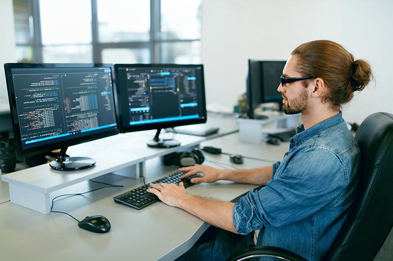Programmering. Man die aan Computer in IT-Bureau werkt, Zittend aan Bureau die Codes schrijft. 程序员输入数据代码，在软件开发公司从事项目工作. Afbeelding van hoge kwaliteit.